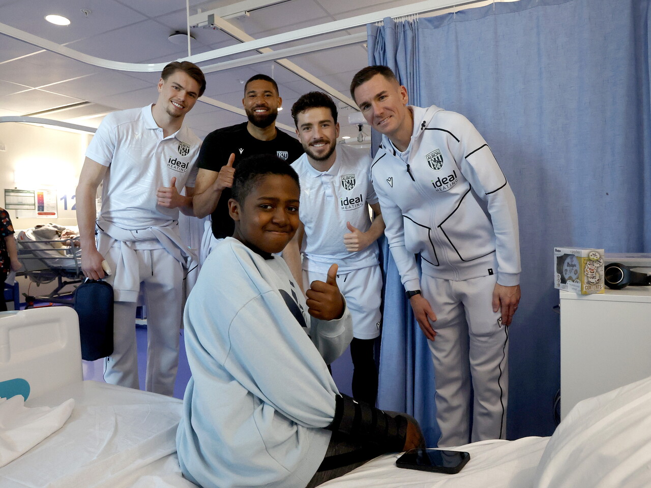 Four WBA players pose for a photo with a poorly child on a ward at Midlands Met hospital 