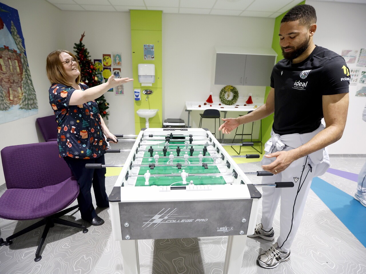George Campbell playing table football with an NHS staff worker on a ward at the Midlands Met hospital