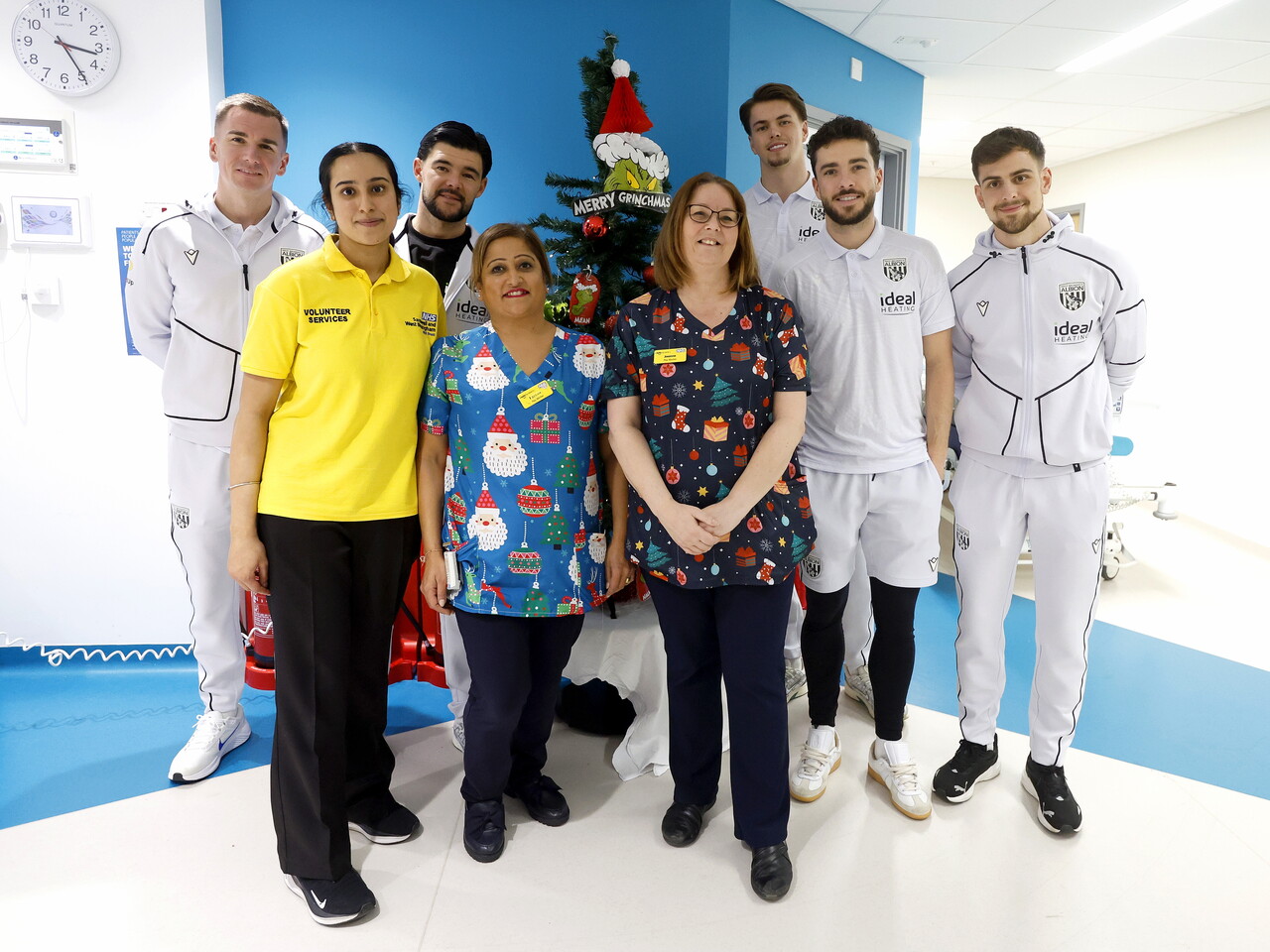Five WBA players posing for a photo with NHS staff members on a ward at the Midlands Met hospital