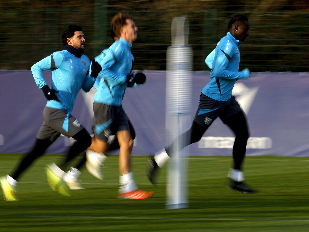 Three players running forward in a line during a training session