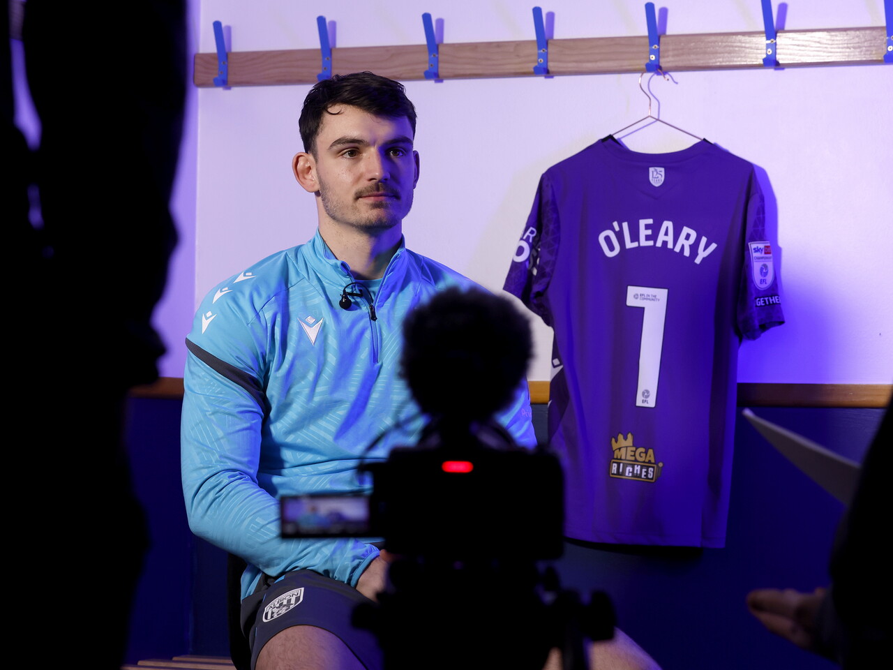 Max O'Leary being interviewed by WBA TV while sat next to his No.1 shirt in a dressing room