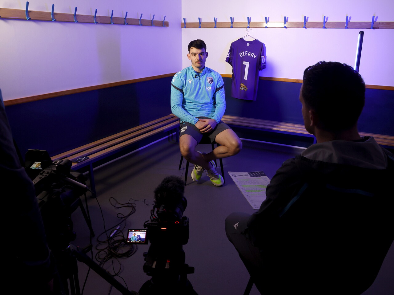 Max O'Leary being interviewed by WBA TV while sat next to his No.1 shirt in a dressing room