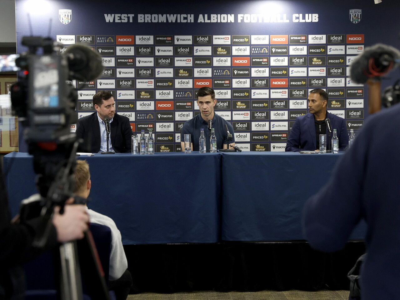 Eric Ramsay, Shilen Patel and Ian Skidmore sat up on stage on a press conference table 