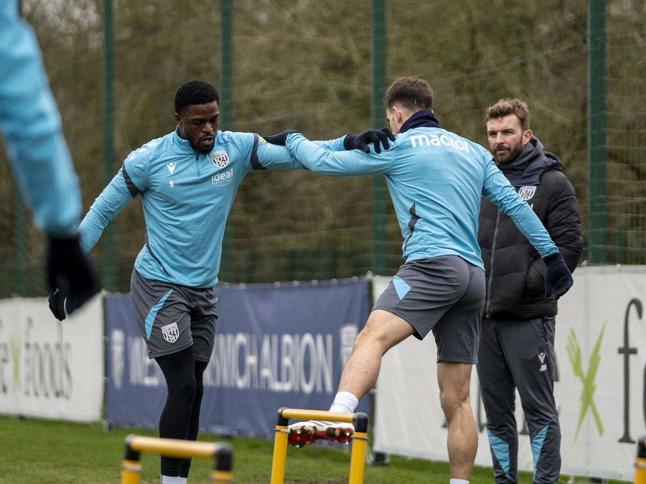Josh Maja and Jayson Molumby stretching in front of James Morrison during a training session