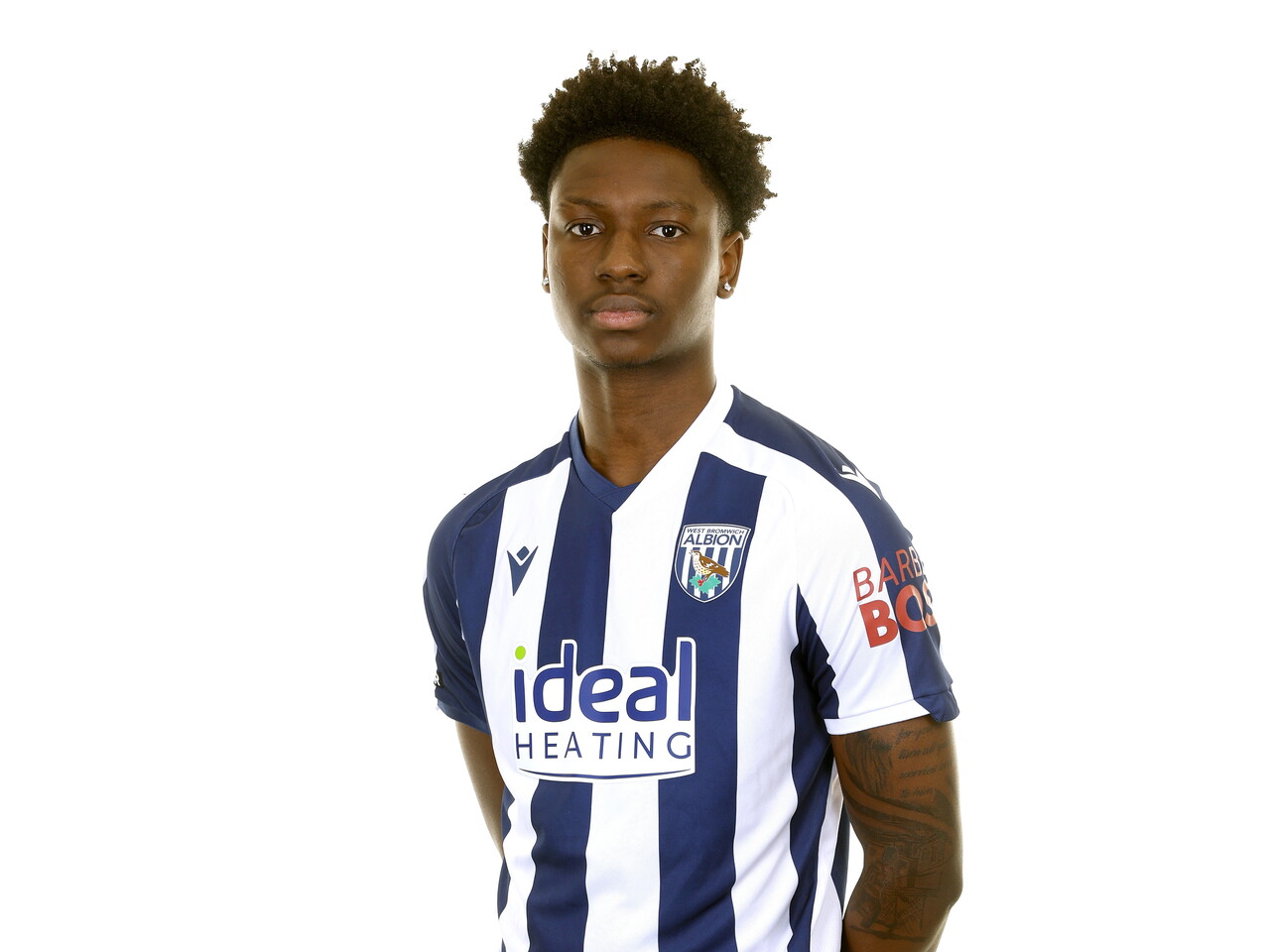 Jamaldeen Jimoh-Aloba smiling at the camera while stood in front of a white background in the home kit