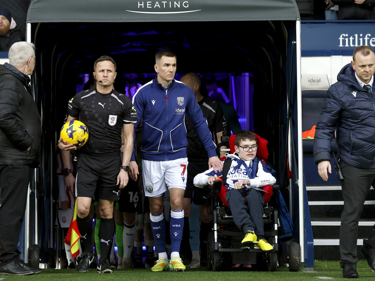 Jed Wallace walking out of the tunnel with a disabled WBA fan