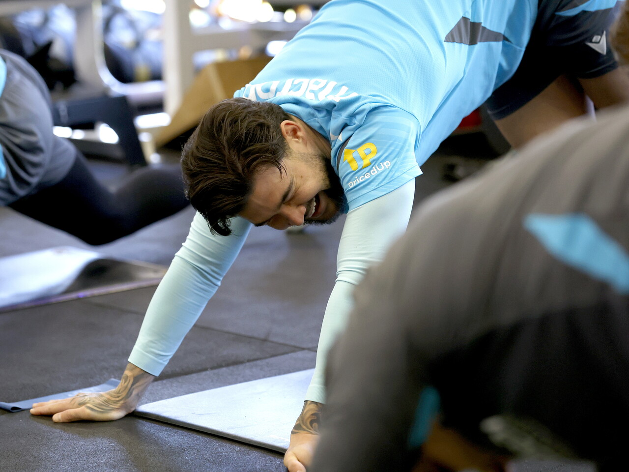 Alex Mowatt stretching and laughing while in the gym