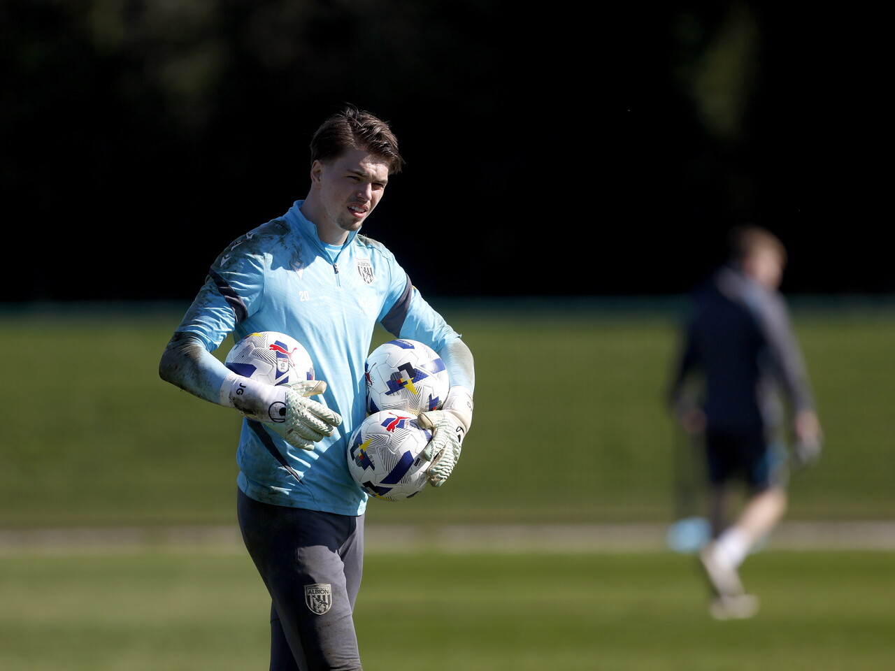 Josh Griffiths holding several footballs during a training session