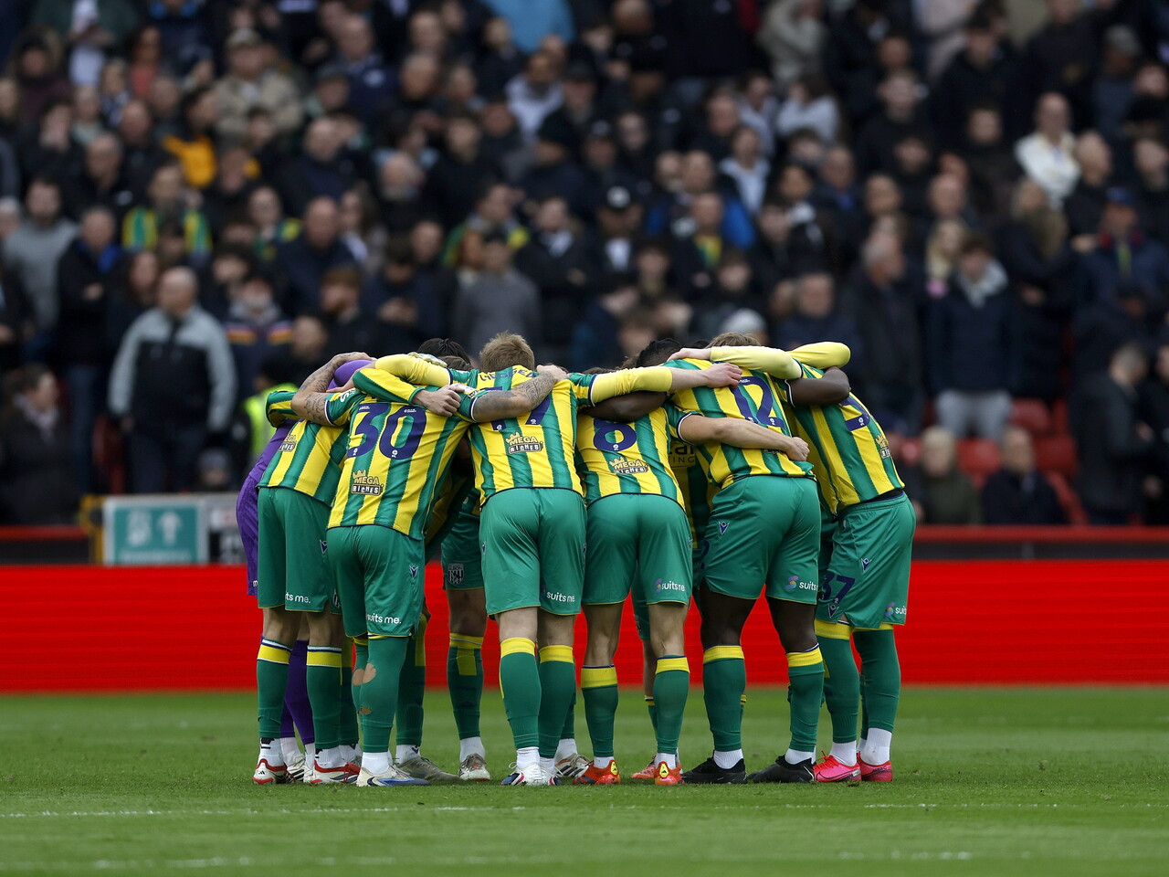 WBA in a team huddle in the green and yellow away kit before the Sheffield United game