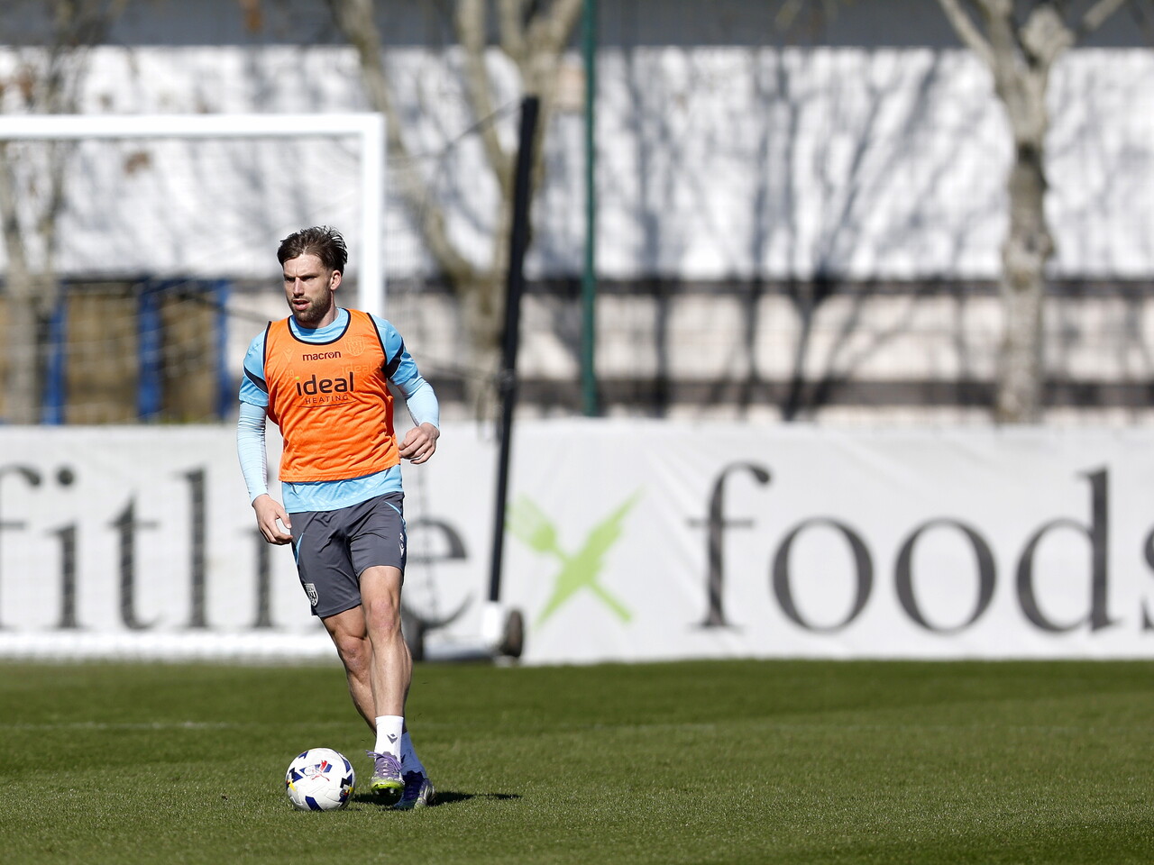 Charlie Taylor on the ball during a training session in front of Fitlife Foods branding around the side of the pitch 