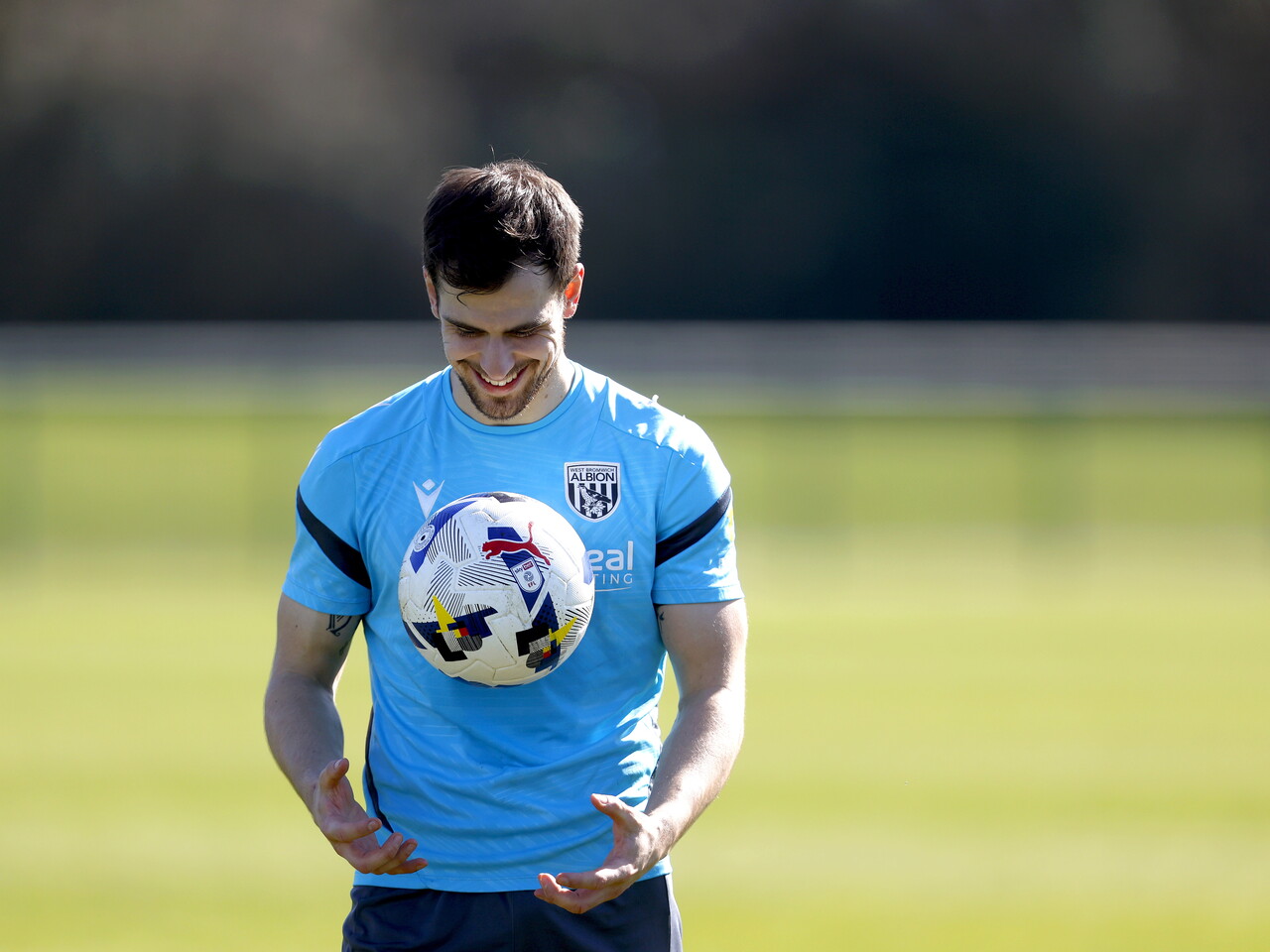 Jayson Molumby smiling while holding a ball during a training session