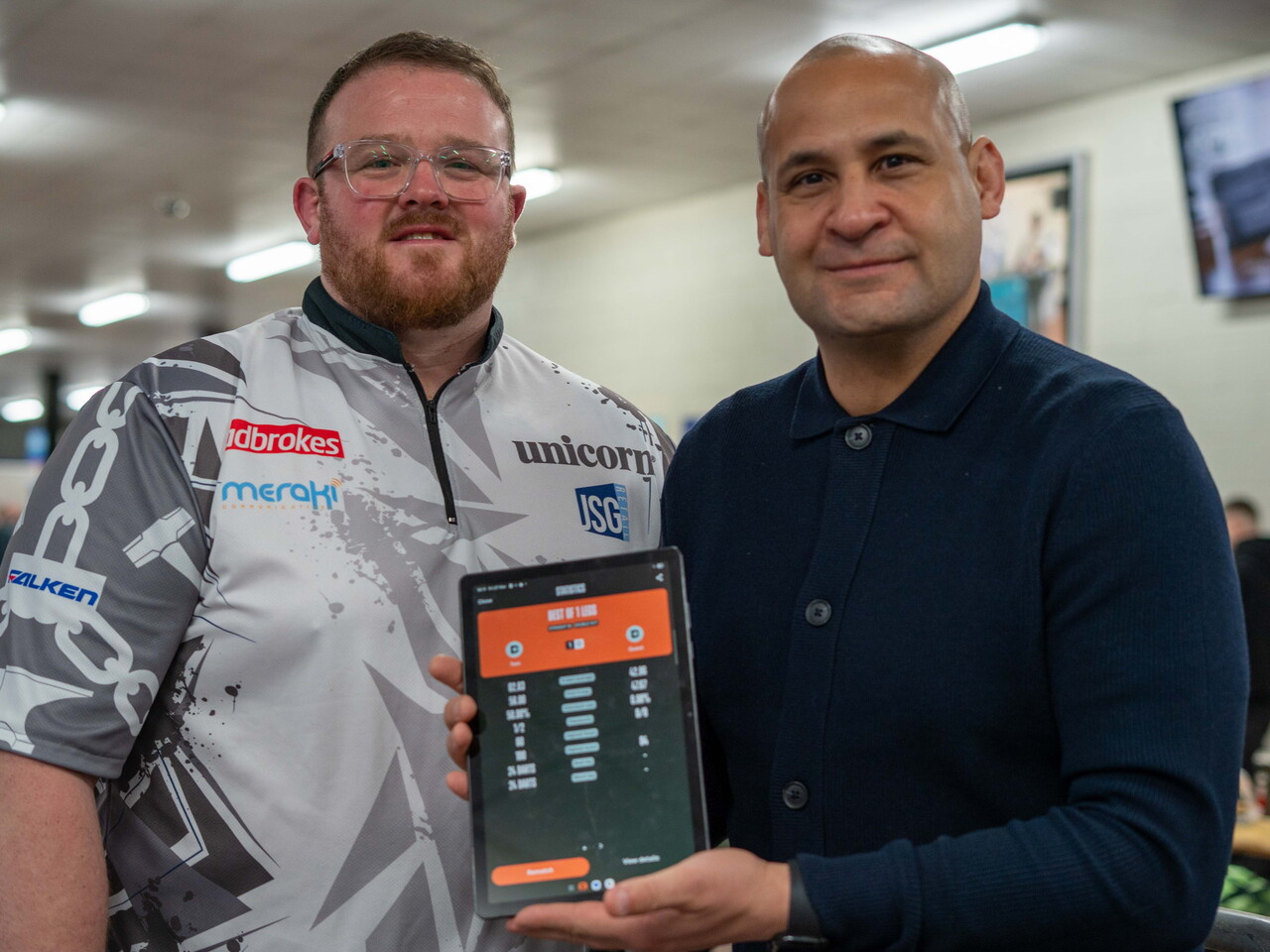 Tom Bissell & Nigel Quashie holding up a tablet with the score from their match.