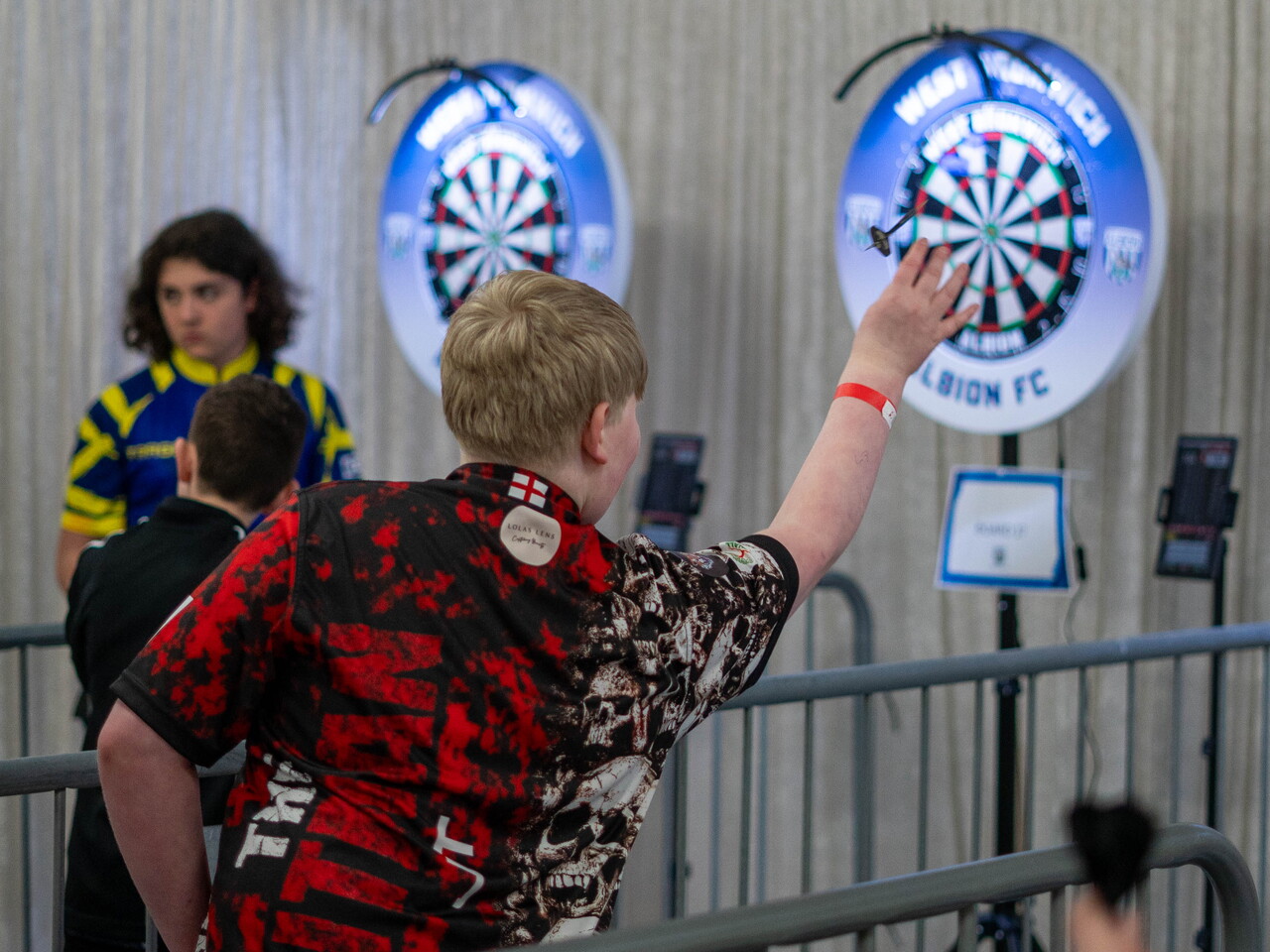 Junior darts players throws darts.