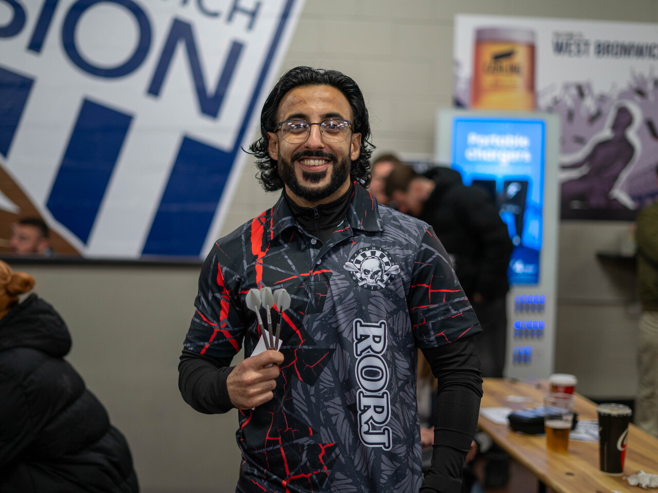 Smiling adult darts player holding his darts