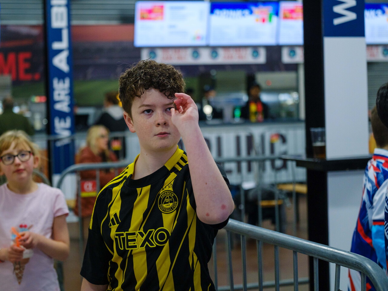 Junior darts player taking aim, with dart at eye level.