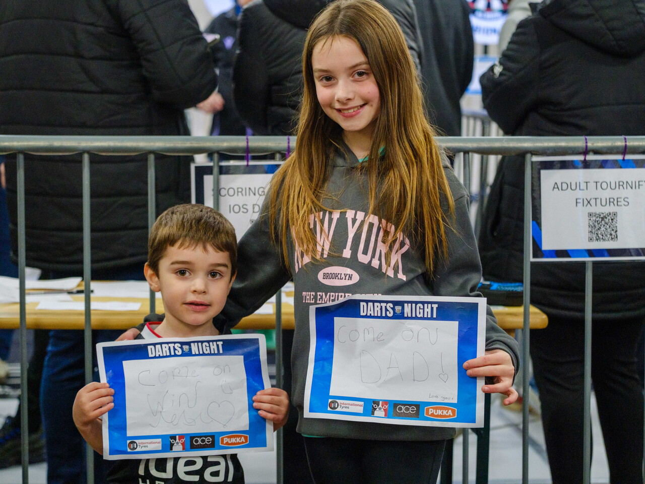 Two children holding signs with a message to their father.
