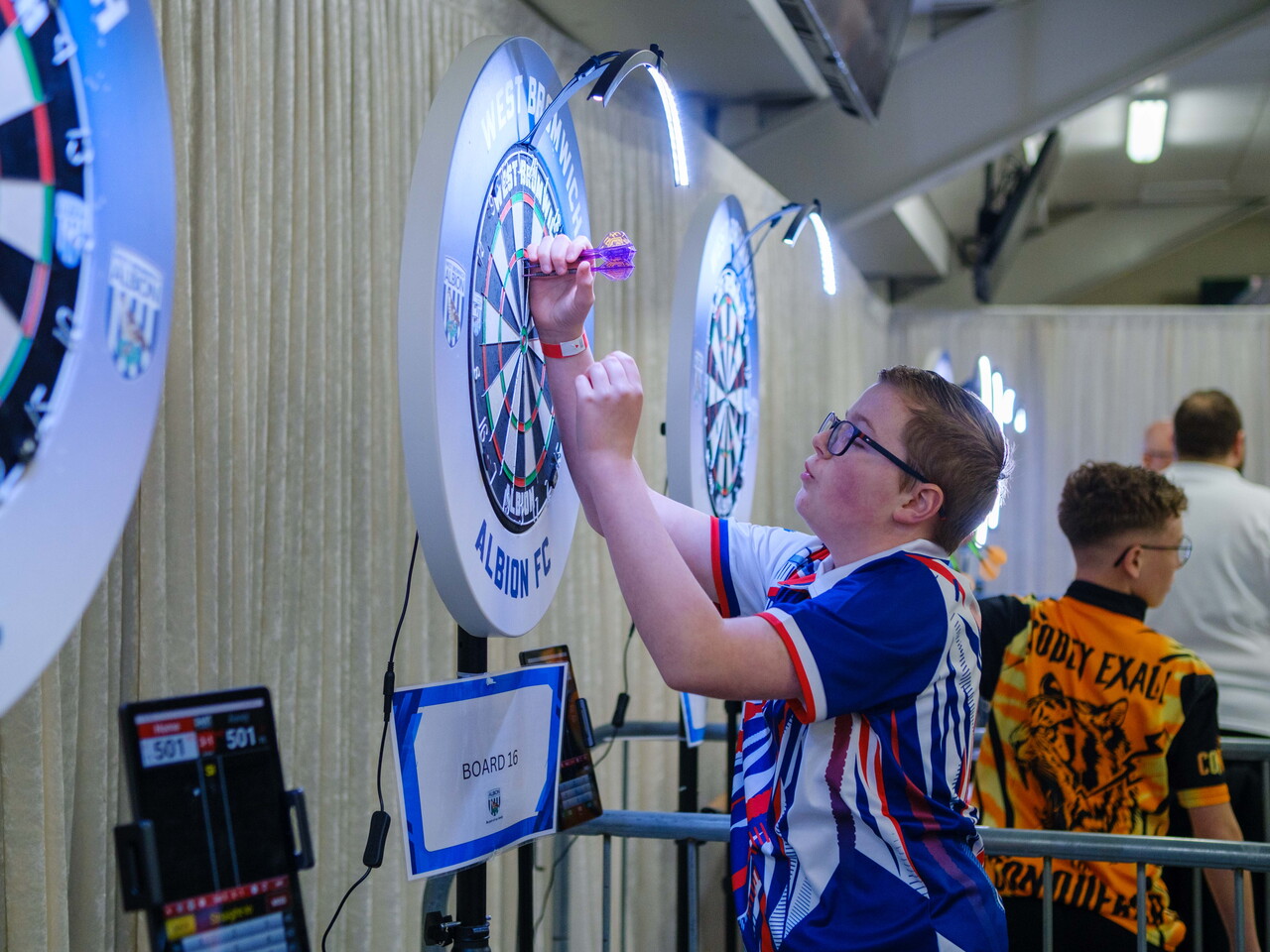 Junior player taking his darts out of the board.