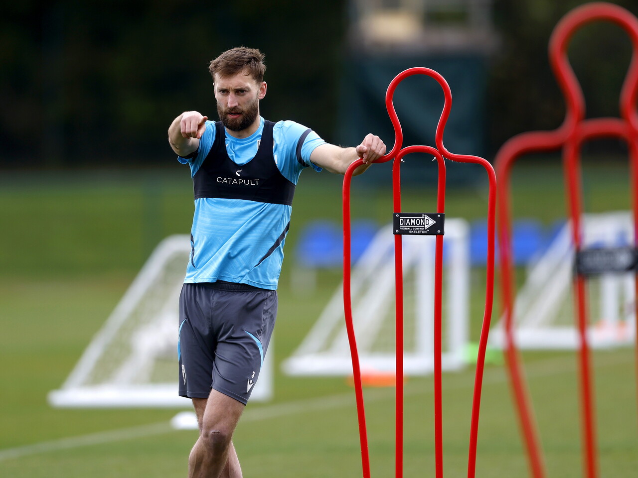 Nat Phillips pointing while stood by a mannequin during training