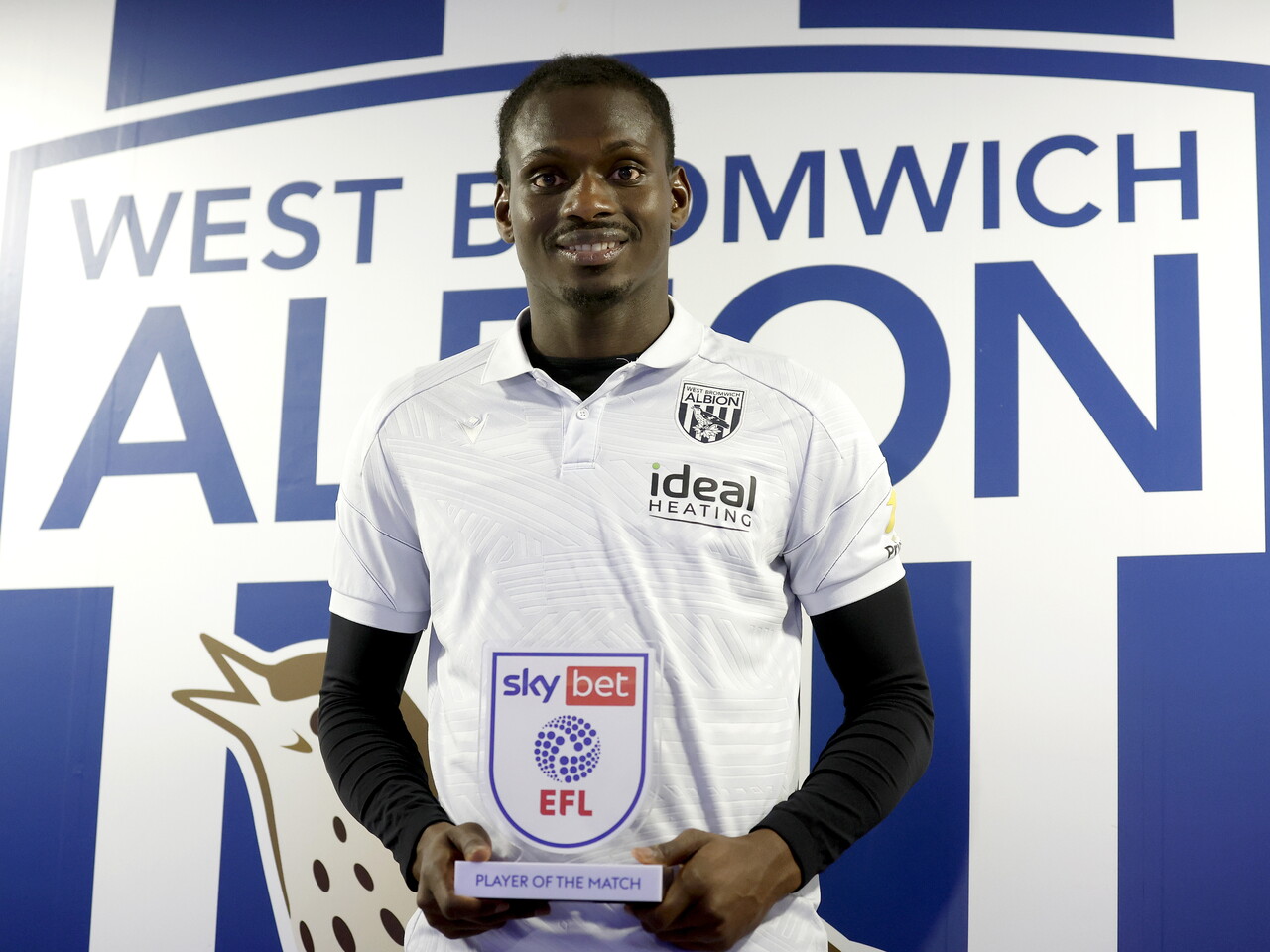 Ousmane Diakité smiling at the camera while holding the Player of the Match trophy 