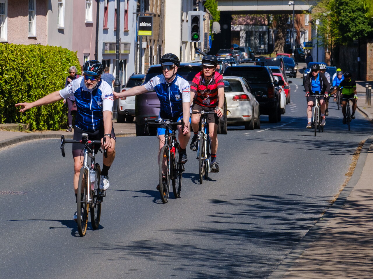Three cyclist signalling to turn right on a high street.