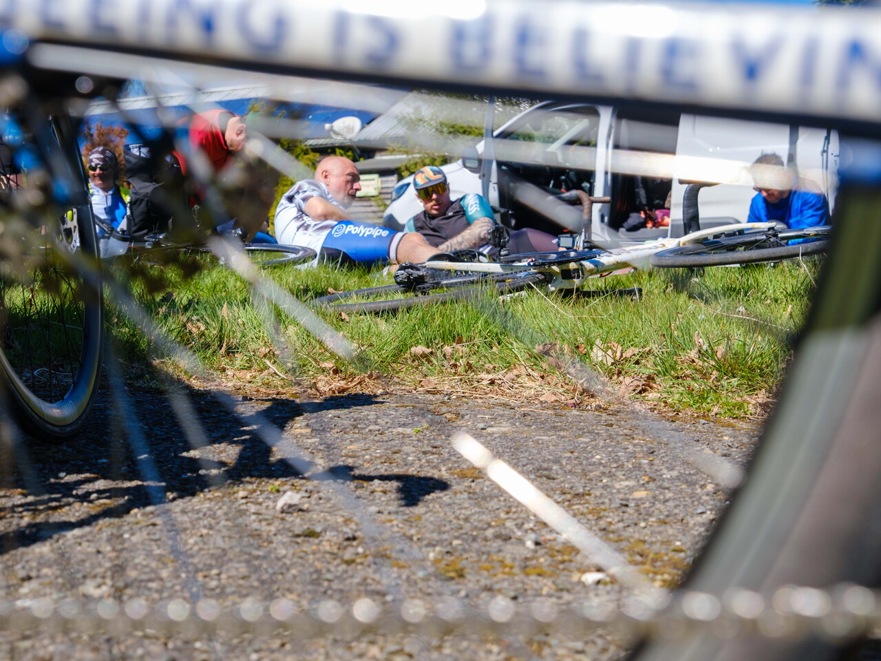 Cyclists laying on grass, shoot through wheel spokes.