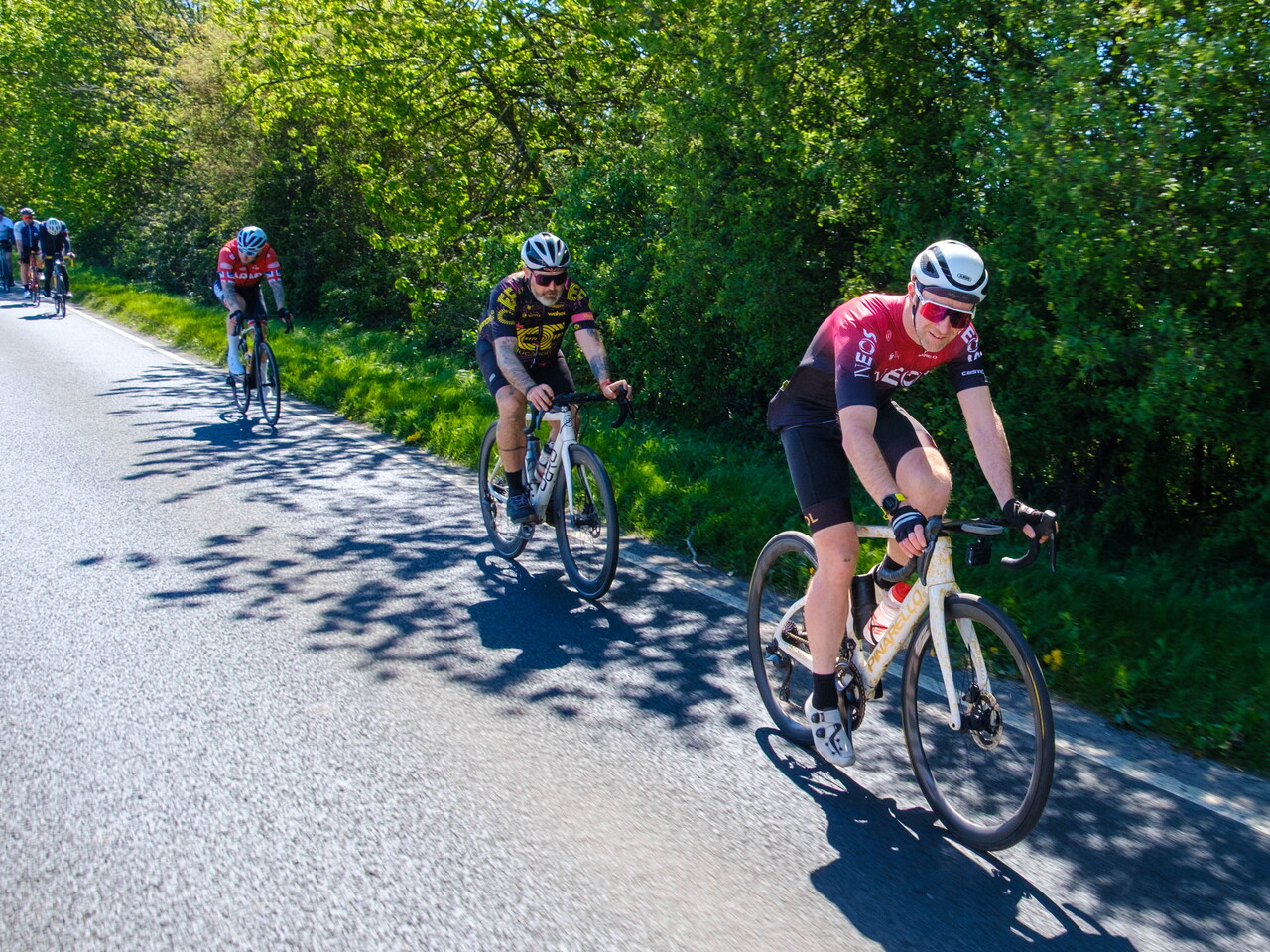 Three cyclist riding down a country road.