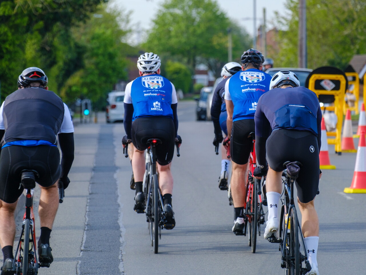 Cyclist riding down a high street with roadworks.