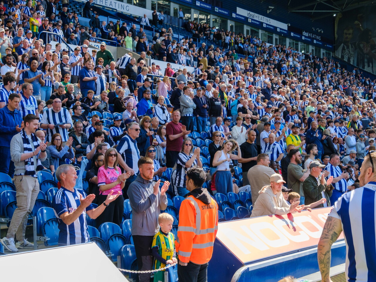 Fans applauding cyclists during lap of honour.