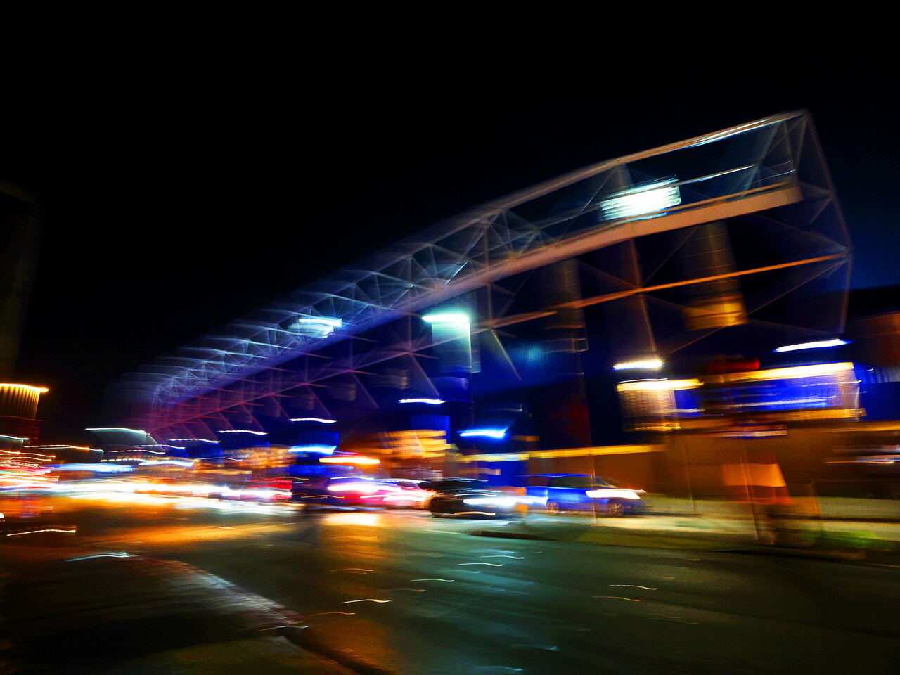 A general shot of the Birmingham Road End at night with cars flying past and bright lights 