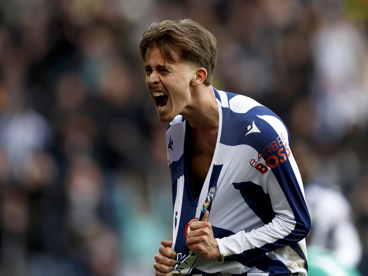 Isaac Price celebrates scoring against Hull at The Hawthorns in the home kit by pulling his shirt down from the neck