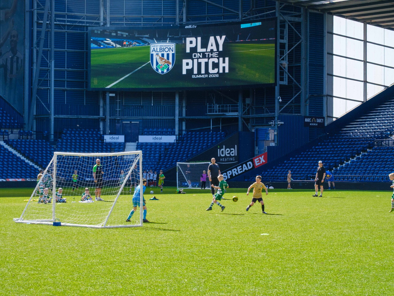 Players on the pitch with WBA Play on the Pitch branding on the Big Screen.