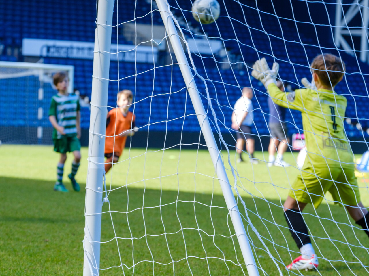Behind the net view of goalkeeper about to make a catch.
