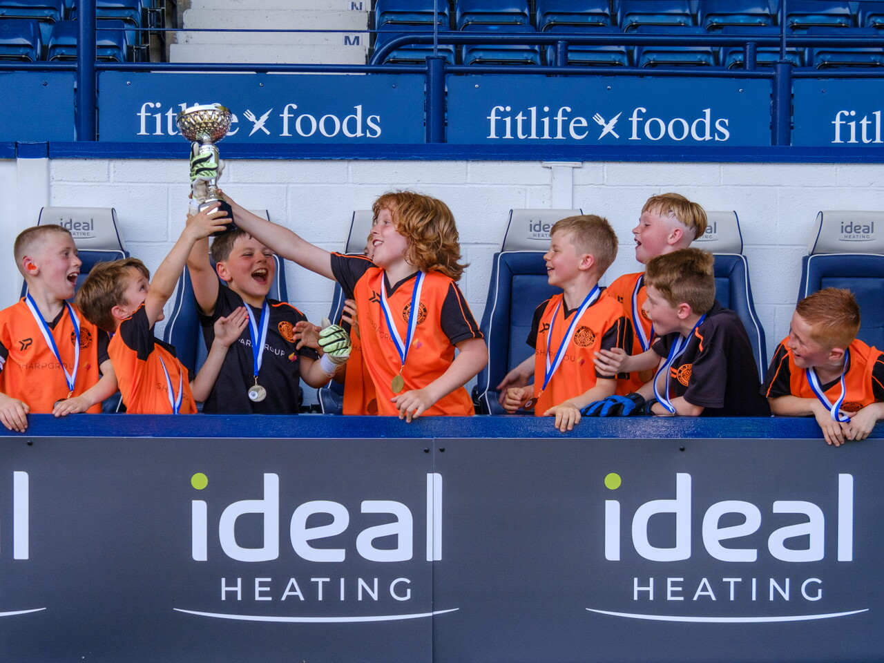 St Kevin's FC U9s celebrating in the dugout with the trophy