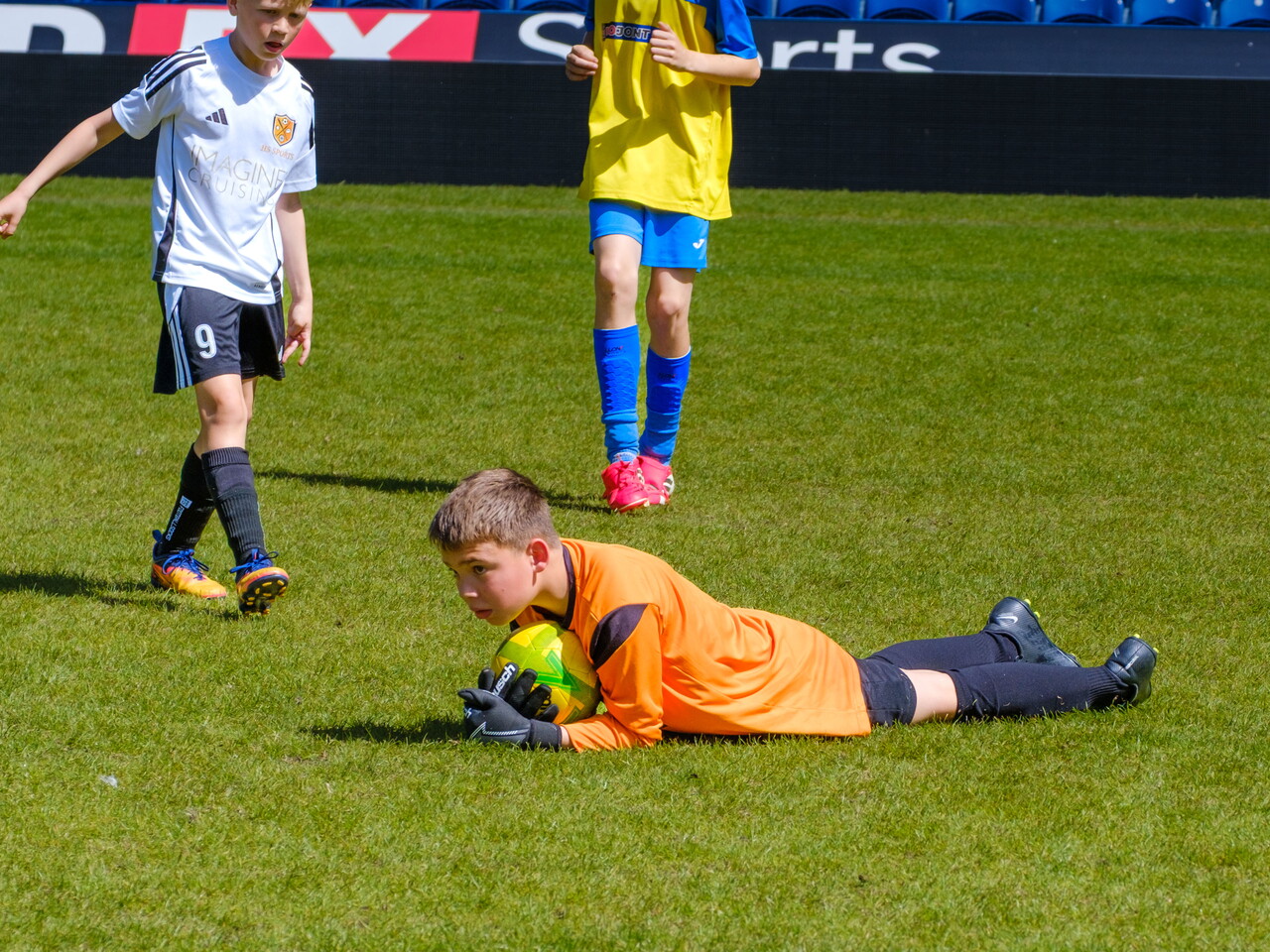 Goalkeeper securing the ball on the ground.