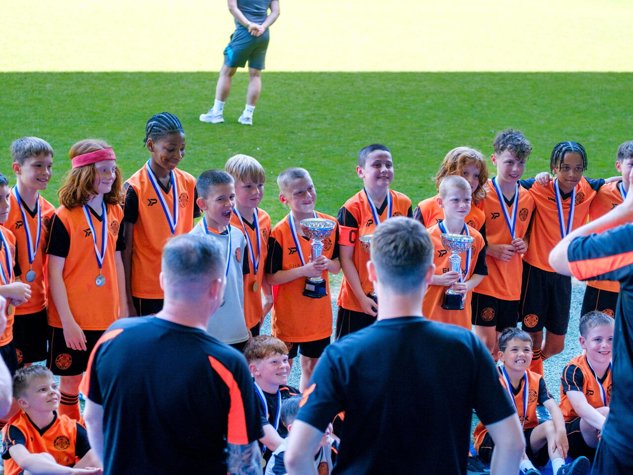 St. Kevin's FC teams holding their trophy with parents and coaches taking photos.
