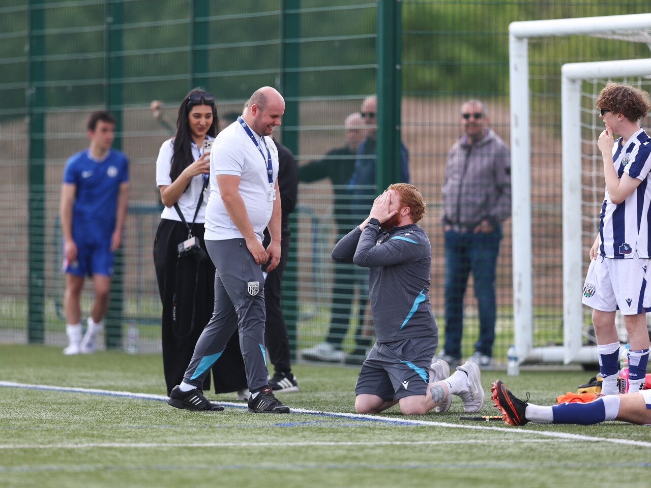 WBA coach kneeling with hands over his eyes, with assistant smiling.