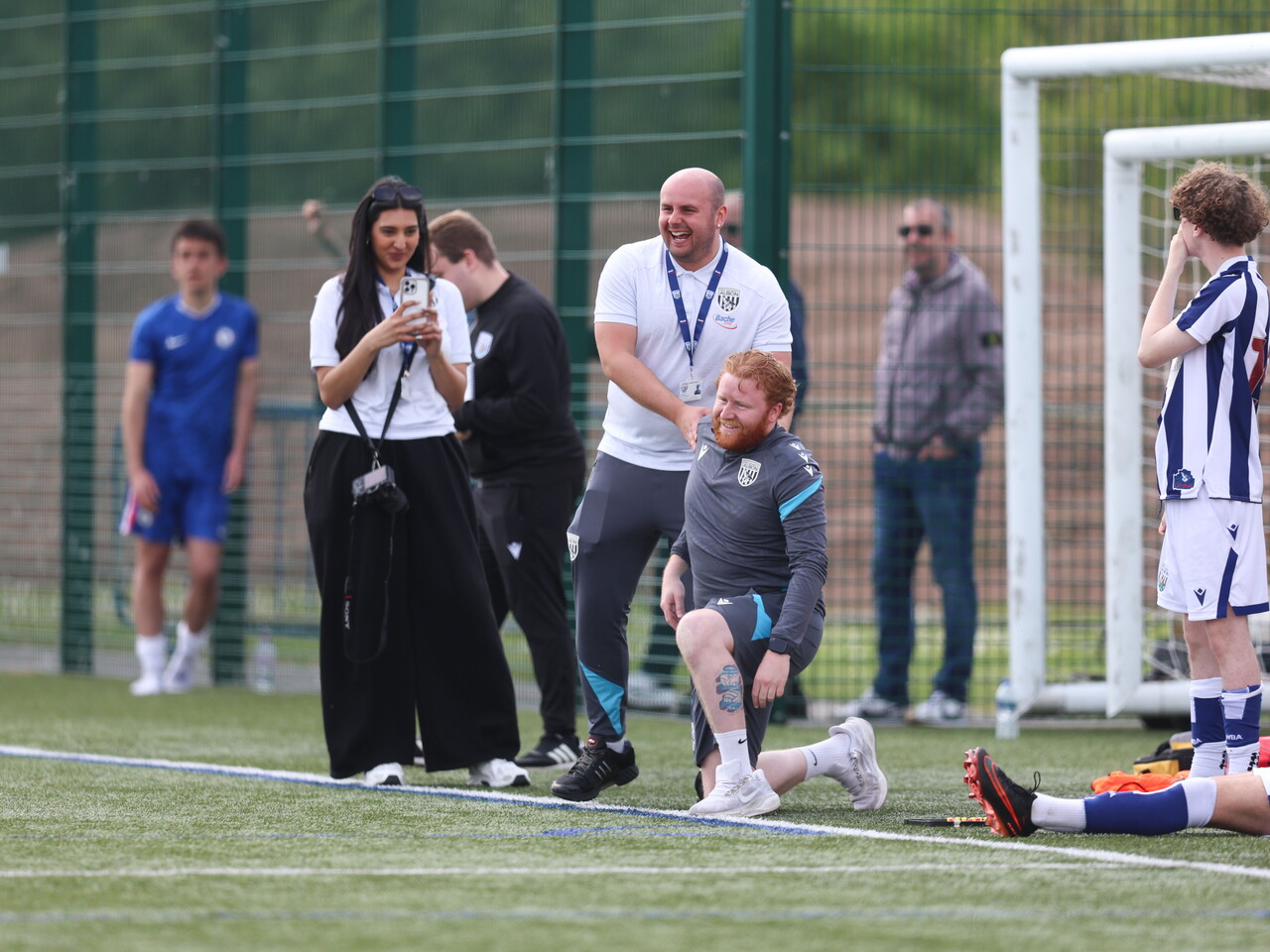 WBA coach kneeling with hands over his eyes, with assistant smiling.