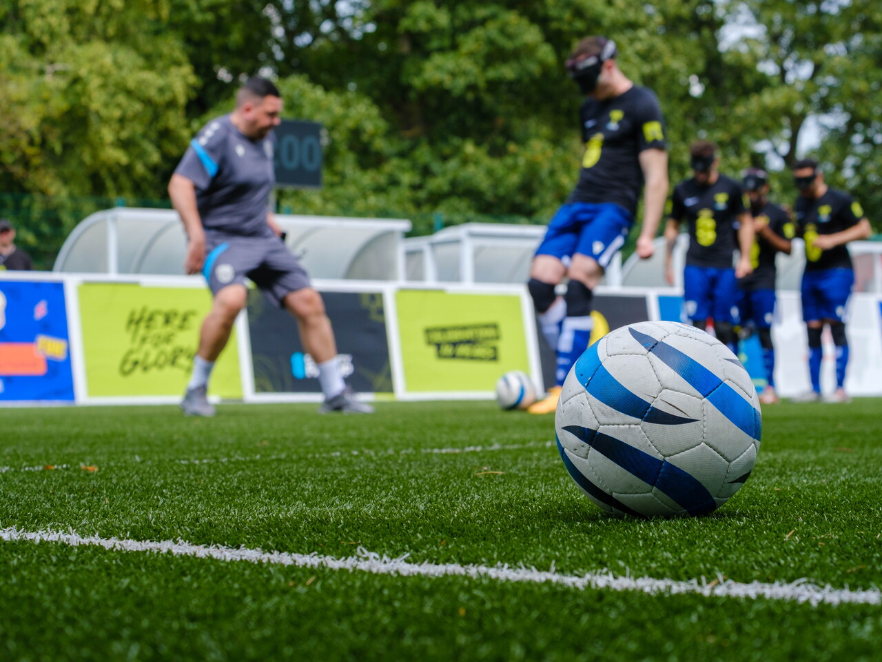 Close-up of ball with WBA Blind players warming up in the background.