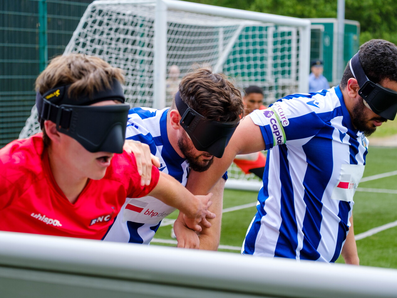 Close-up of Mo Ahmed, Kieran Clarke & RNC player attempting to gain the ball next to the pitch boards.
