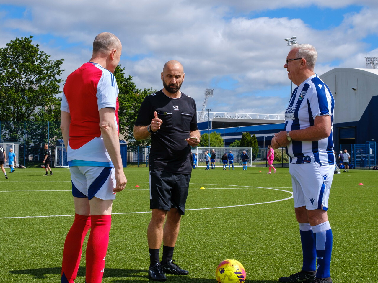 Arsenal and Cancer Kickers captains with referee discussing coin toss.