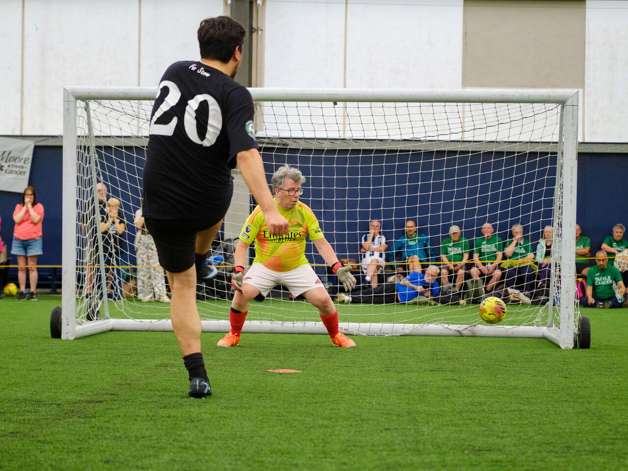 Moore than Cancer player striking his penalty with Arsenal goalkeeper attempting to dive for it.