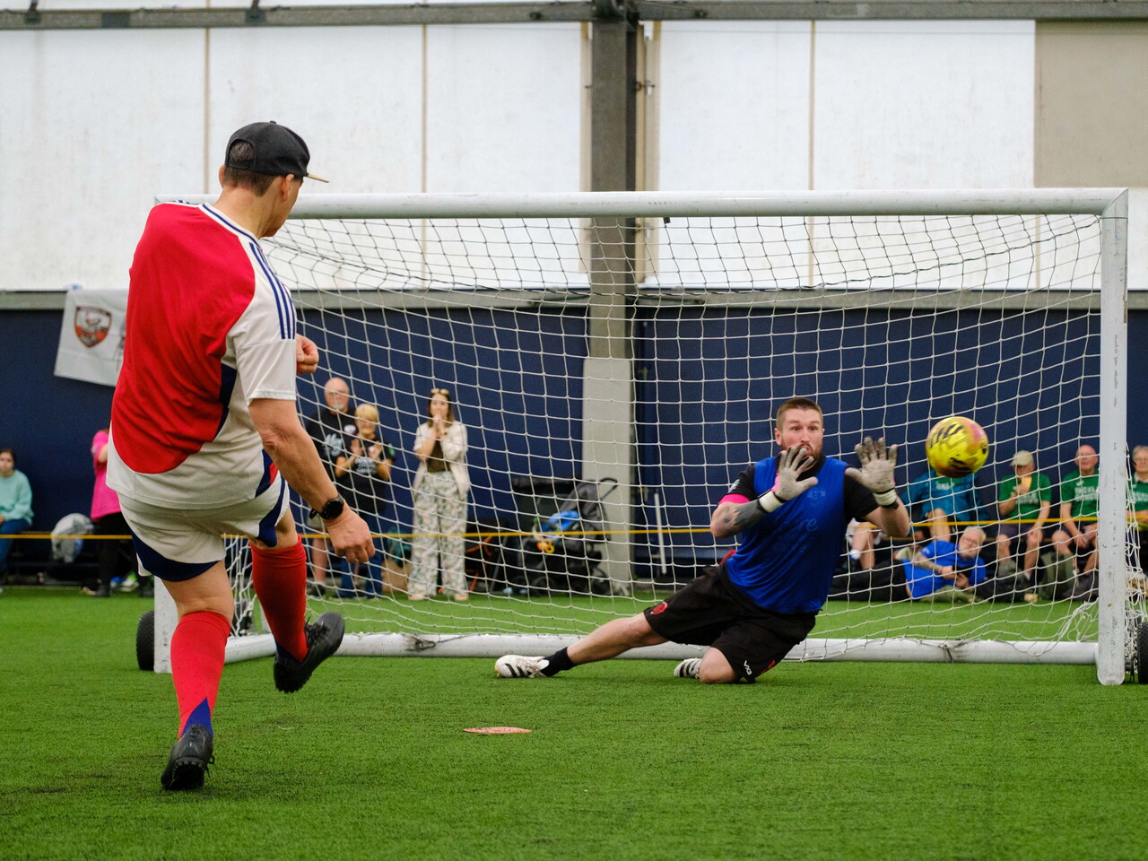 Arsenal player striking his penalty with Moore than Cancer goalkeeper attempting to save it.