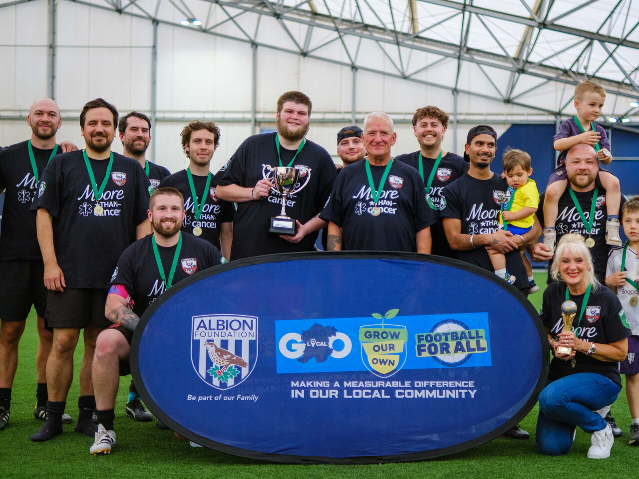 Moore than Cancer with trophy in front of Albion Foundation branded banner.