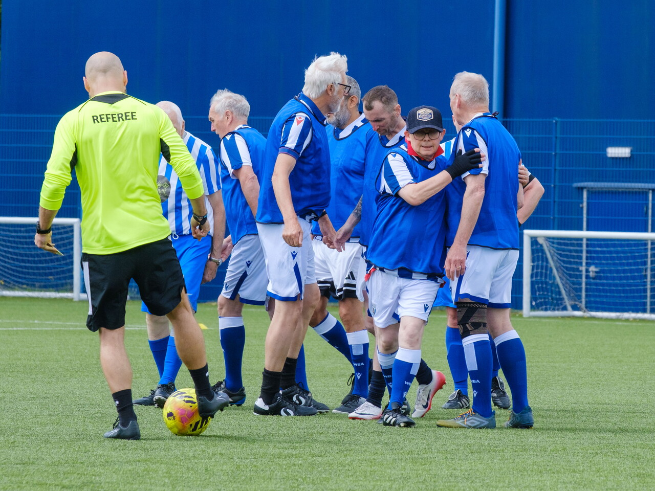 Close-up of Cancer Kickers players in blue bibs, celebrating a goal