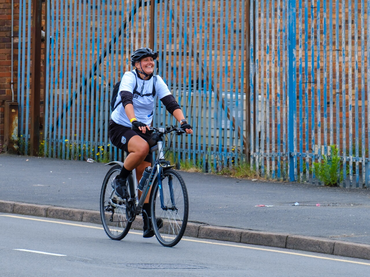 A smiling cyclist rides along a roadside route during the challenge.