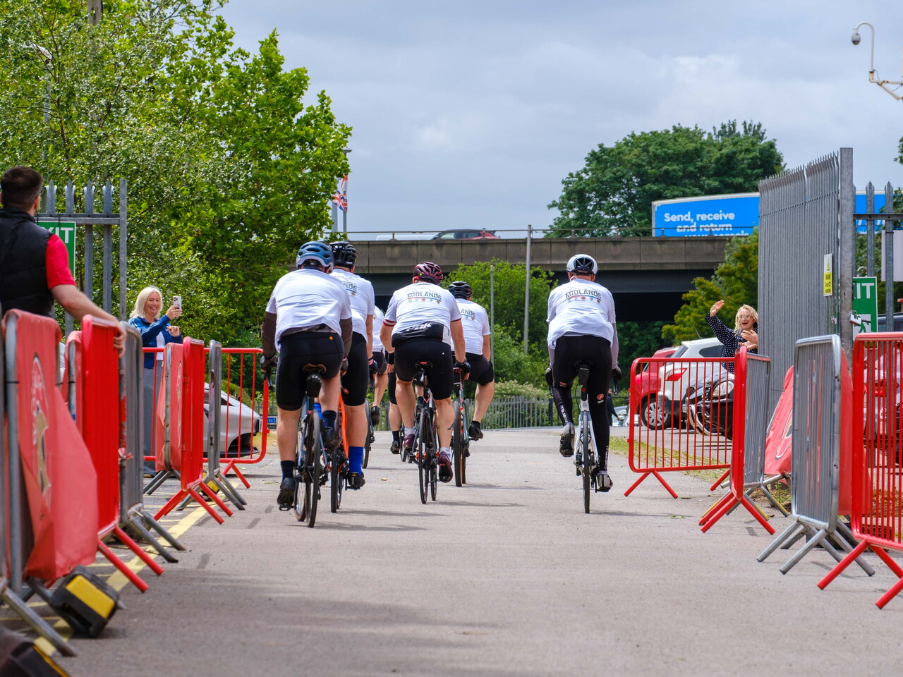  Cyclists ride away from the camera out of Pallet-Track Bescott Stadium.