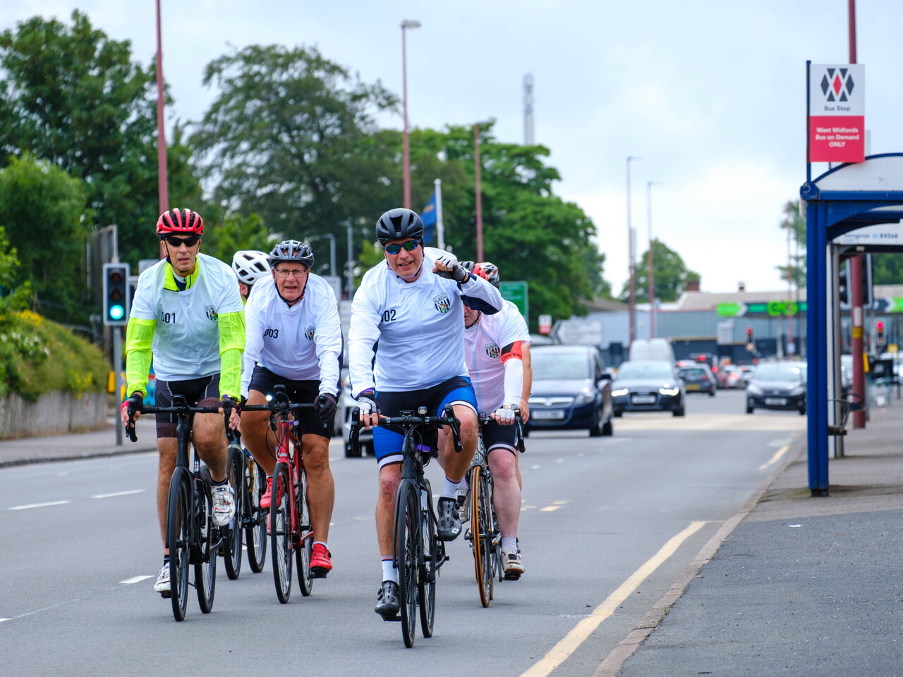 Group of cyclists riding together on a busy road entering The Hawthorns