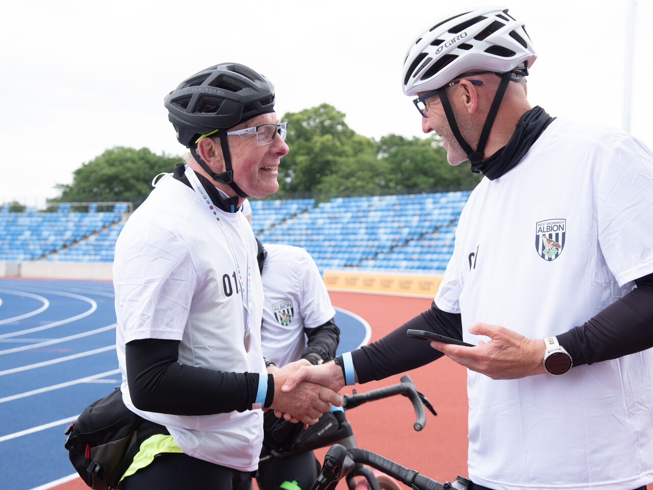 Two cyclists shake hands and chat after completing the event.