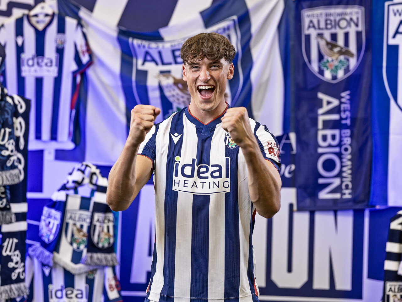 Barney Stewart in the home kit celebrating towards the camera while stood in front of an Albion back drop with plenty of WBA branding
