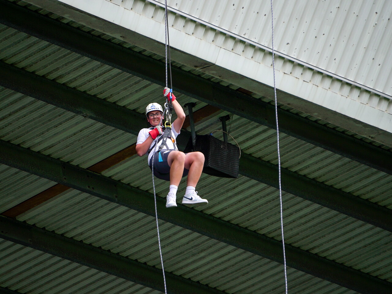 Participant wearing a helmet, harness and safety gloves abseils from the roof of The Hawthorns, suspended on ropes beneath the stadium structure.